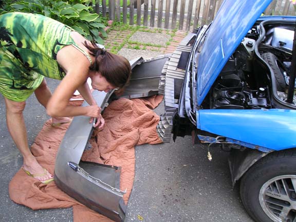 1984 Pontiac Fiero front bumper removed, woman in green dress working on it