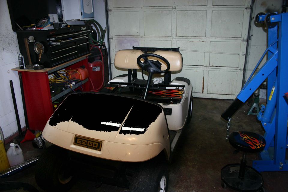 EZGO golf cart with flame decals on the seat back, parked in a garage
