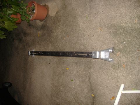 1996 Ford Bronco - A metal bracket with numerous holes and a unique end, possibly a specialized tool, is shown on a concrete surface.
