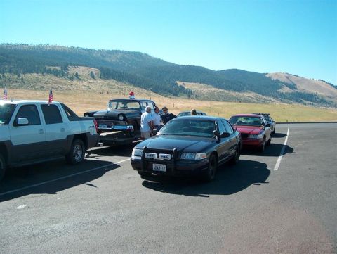 2001 Ford Crown Victoria - Several vehicles are parked in a lot with a mountainous landscape under a clear blue sky.