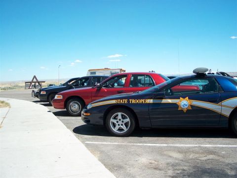 2001 Ford Crown Victoria - Several law enforcement vehicles are parked in a lot under a clear blue sky.