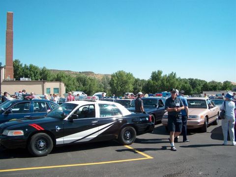 2001 Ford Crown Victoria - A police car is parked at an outdoor event with other vehicles and people.