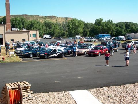 2001 Ford Crown Victoria - Outdoor car show or event with numerous vehicles and attendees gathered in a parking lot.