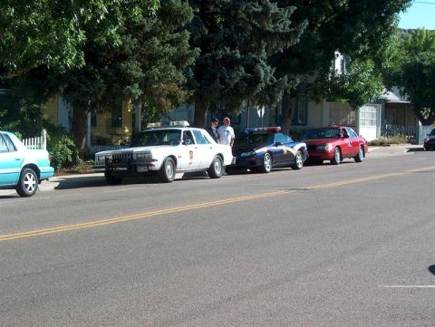 2001 Ford Crown Victoria - Several police vehicles are lined up on the side of a residential street.