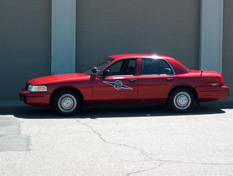 Red sedan, looks like a police car, parked outside a building