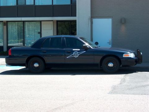 2001 Ford Crown Victoria - A dark 2001 Ford Crown Victoria police car is parked in front of a building.