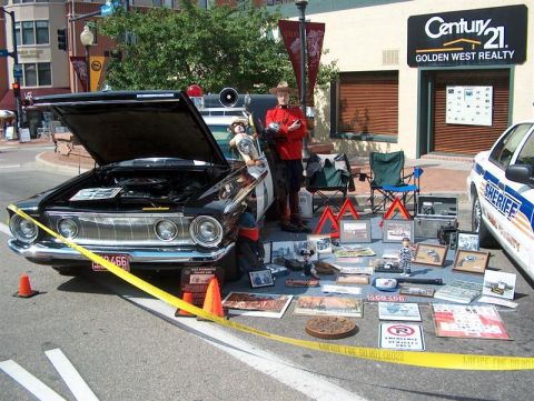 2001 Ford Crown Victoria - A display of items is laid out on the street next to a vintage police car and a modern sheriff's vehicle.