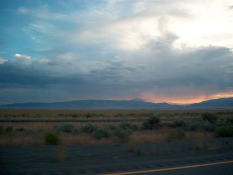 2001 Ford Crown Victoria - A vast desert landscape unfolds under a dramatic sky, with distant mountains silhouetted against the sunset.