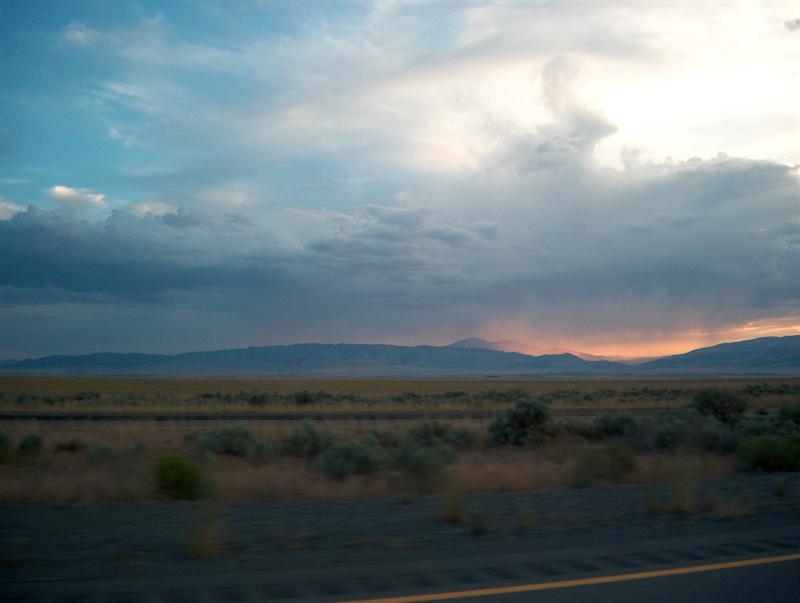 Desert landscape with mountains under a dramatic cloudy sky at sunset
