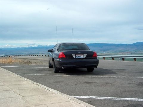 2001 Ford Crown Victoria - A dark 2001 Ford Crown Victoria is parked on the side of a road with a scenic mountain view in the background.