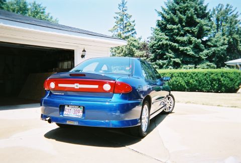 1996 Ford F-150 - Rear view of a blue sedan parked in a driveway next to a garage.