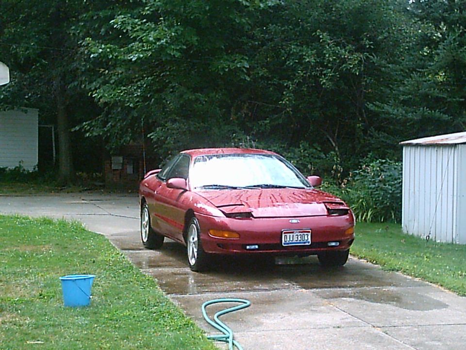 Red 1993 Ford Probe coupe parked on a wet driveway, front view