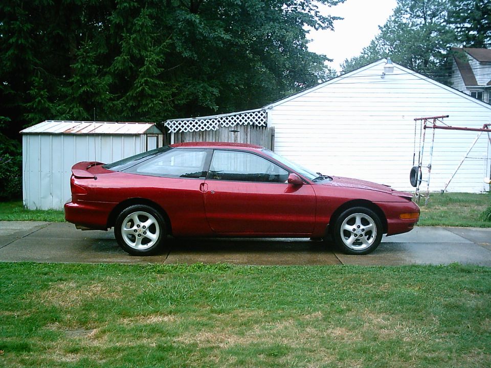 Red 1993 Ford Probe coupe parked on a driveway, side view
