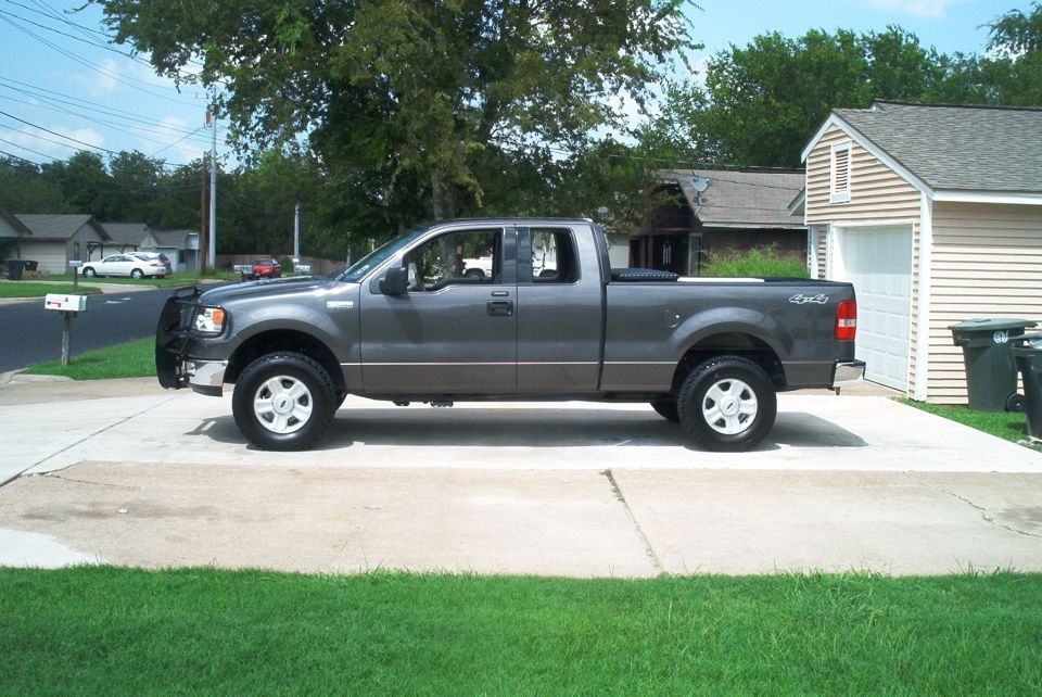 Dark gray Ford F-150 extended cab 4x4 pickup parked in a driveway, side view