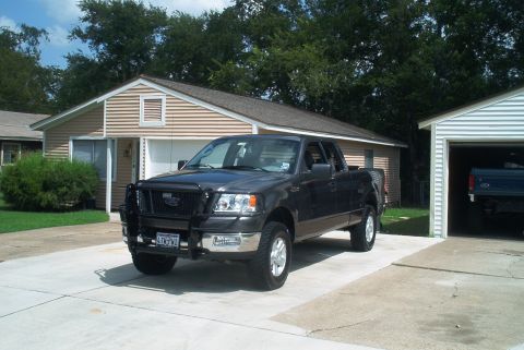 1986 Ford Bronco - This dark gray 2004 Ford F-150 pickup truck is parked in a driveway in front of a house and garage.