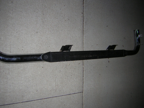 Exhaust pipe with two mounting brackets, resting on a concrete surface