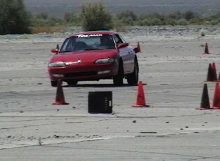 Red 1996 Ford Probe in a slalom course with cones