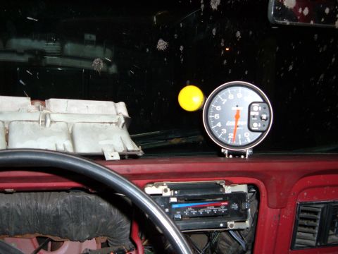 1978 Ford Bronco - The interior of a vehicle shows a tachometer and climate controls, with a dirty windshield.