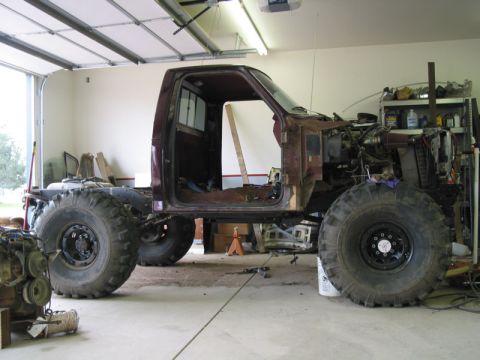 1981 Ford Bronco - This custom pickup truck chassis features oversized tires and a maroon cab, appearing to be in the process of modification or a project bui…