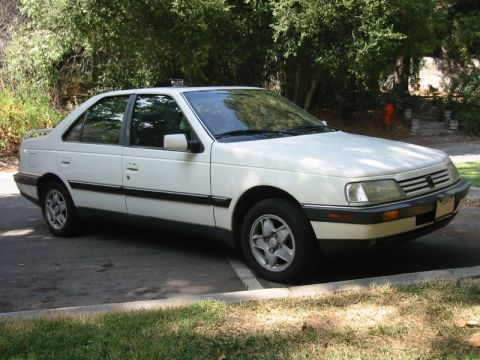 1989 Peugeot 405 - This white 1989 Peugeot 405 sedan is seen parked outdoors with a natural backdrop.