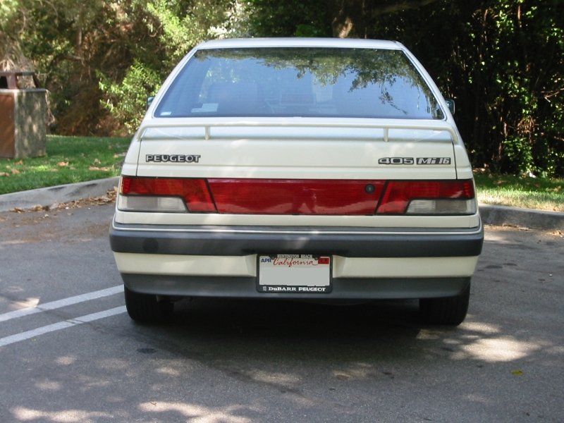 Rear view of a white Peugeot 405 Mi16 sedan parked on asphalt