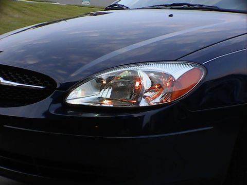 2000 Ford Taurus - Front corner view of a dark blue 2000 Ford Taurus, highlighting the headlight assembly.