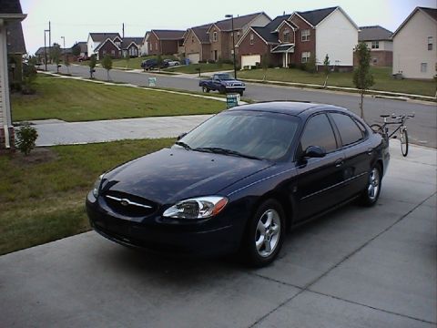 2000 Ford Taurus - A dark blue sedan is parked in a suburban driveway.