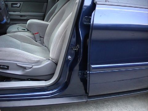 2000 Ford Taurus - The interior of a blue 2000 Ford Taurus is visible, focusing on the front seats and the open driver's side door.