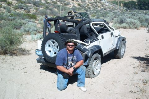 1986 Ford Bronco - Man poses with a white Jeep Wrangler in a desert landscape, with another Jeep visible behind.