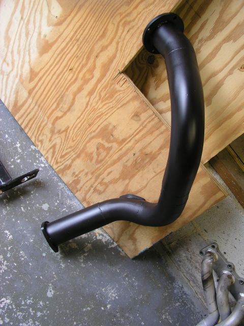 1996 Ford Probe - Exhaust pipe section with flanges, resting on plywood.