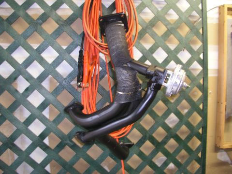 1996 Ford Probe - A turbo exhaust manifold with a wastegate, wrapped in heat tape, is hung on a green lattice wall.