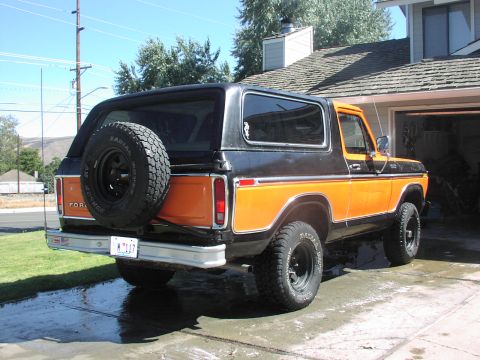 1979 Ford Bronco - The rear of a two-tone Ford Bronco is parked in a driveway next to a house.