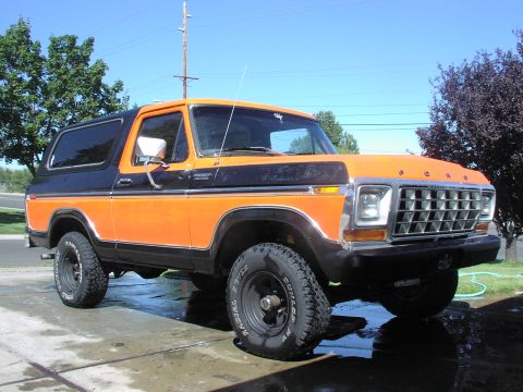 1979 Ford Bronco - This two-tone orange and black Ford Bronco is shown from the front three-quarter angle.