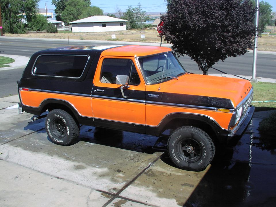 Orange and black Ford Bronco parked on a wet driveway