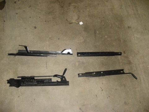 1995 Ford Mustang - Four black metal car seat rails are laid out on a concrete surface.