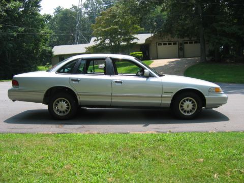 1985 Ford LTD Crown Victoria - Side profile of a silver sedan, appearing to be from the mid-1990s.