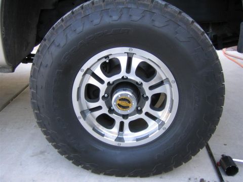 1999 Ford F-250 - This image shows a close-up view of a vehicle's wheel and tire, an aggressive tread pattern and a multi-spoke alloy rim.