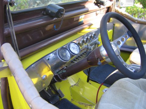 1990 Ford Bronco - interior of an open yellow Jeep shows a polished metal dash with aftermarket round gauges, a black steering wheel, and tan seats.