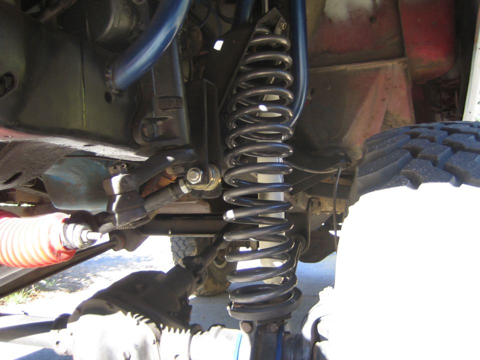 Close-up of a vehicle's coil-spring front suspension and steering linkage underneath