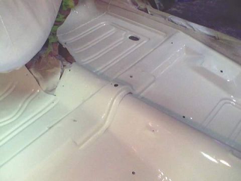 1966 Ford Fairlane - The underside of a vehicle's floor pan is painted white, showing ribbed details and mounting points.
