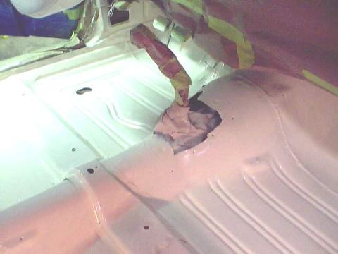 1966 Ford Fairlane - The interior floor of a vehicle is being painted white, showing the ribbed texture and a central opening covered opening.