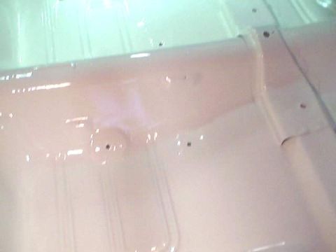 1966 Ford Fairlane - The underside of a car's floor is visible, painted in a light beige color with visible seams and bolt holes.