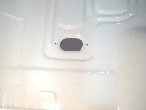 1966 Ford Fairlane - Close-up of a white painted floor pan, showing a grommet hole and stamped metal details.