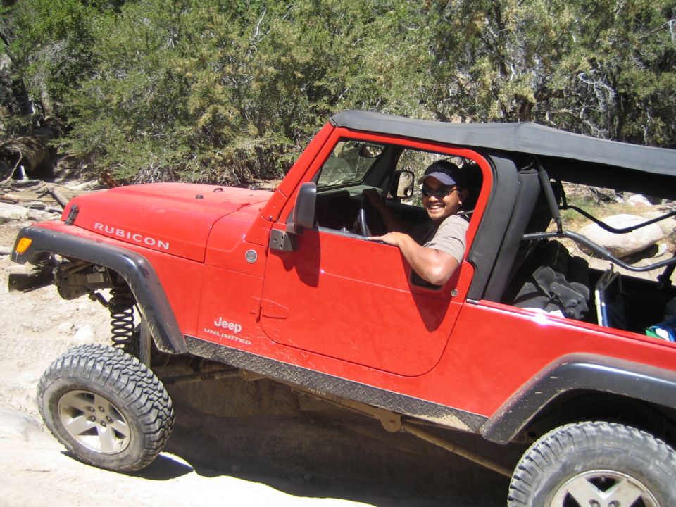 Smiling driver in a soft-top red Jeep Wrangler Rubicon Unlimited
