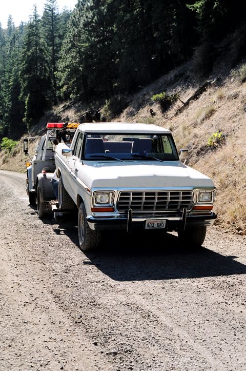 1979 Ford Bronco - A white 1979 Ford F-Series pickup truck is being towed on a dirt road.