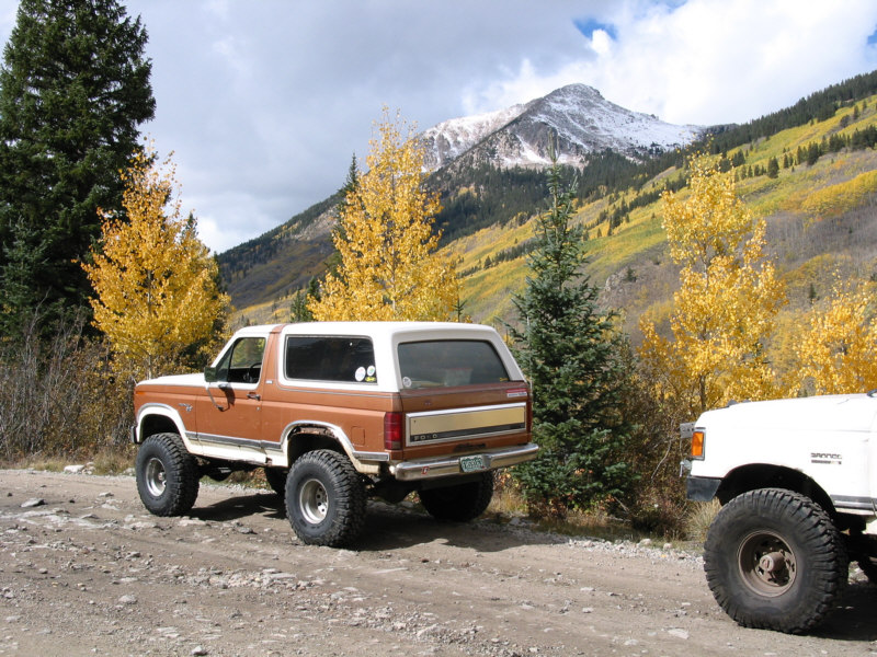 Brown Ford Bronco parked on a dirt road with a mountain in the background