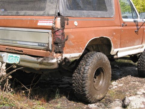 1981 Ford Bronco - Mud covers the rear of a brown 1980 Ford Bronco, obscuring some of its bodywork and taillight.