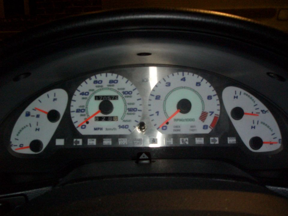 White-face aftermarket gauge cluster with blue numbers, odometer reading 170579, lit at night