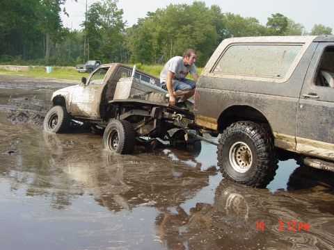 1995 Dodge 1500 - Two trucks are stuck in a muddy area, with one attempting to pull the other out.