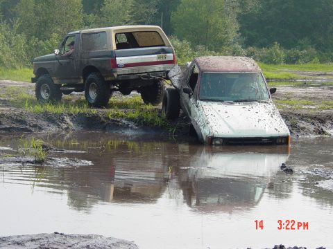 1995 Dodge 1500 - Two off-road vehicles are stuck in a muddy swampy area, with one truck almost completely submerged.